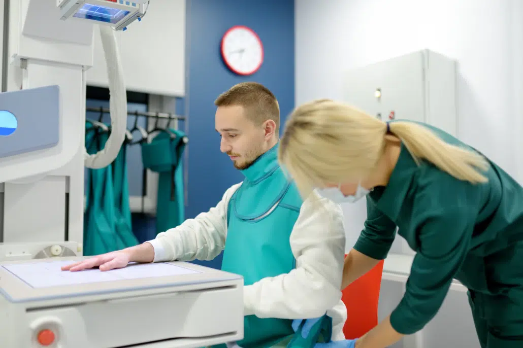 Patient en tablier plombé accompagné d'un professionnel lors d'un examen radiologique Patient en tablier plombé accompagné d'un professionnel lors d'un examen radiologique